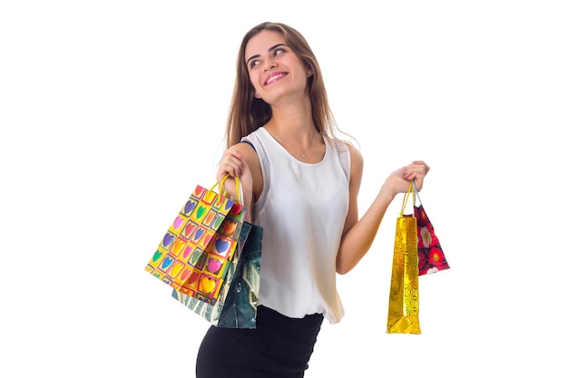 Smiling young woman with long hair in white blouse and black skirt holding shopping bags in studio