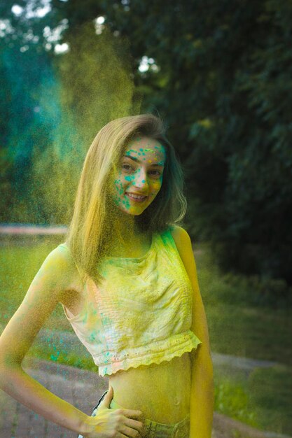 Smiling young woman with powder Holi exploding around her