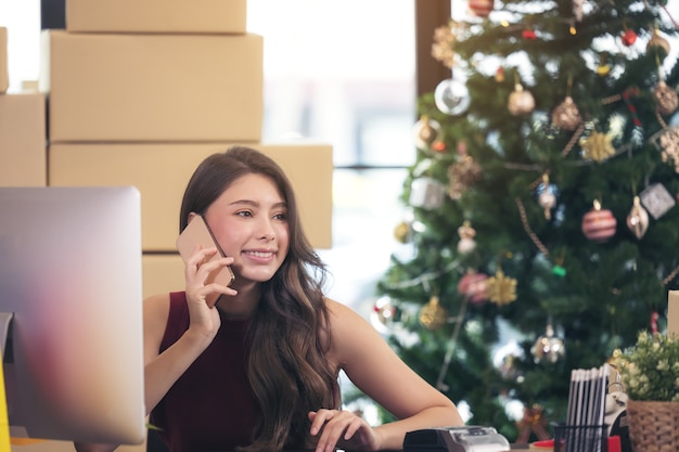 Smiling young woman working from home and talking on smartphone