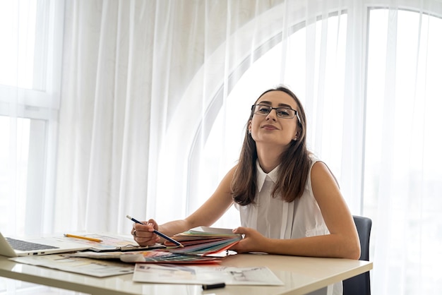 Smiling and young woman working in office with documents