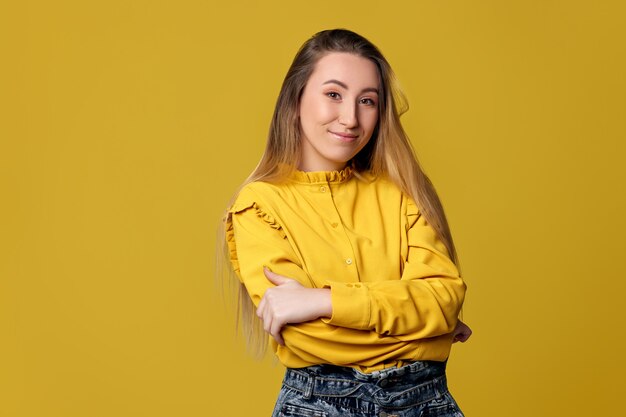 Smiling young woman on yellow background. Human emotions, facial expressions.