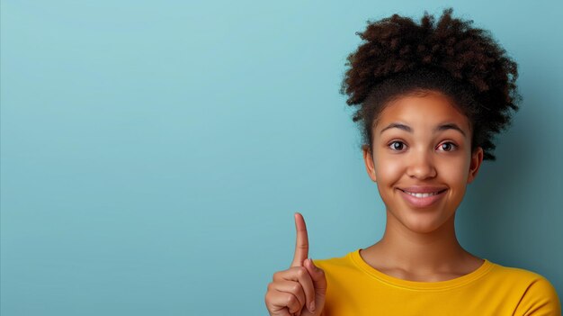 Photo smiling young woman in yellow shirt with idea gesture on blue background