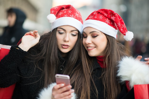 一緒に写真を撮るクリスマス帽子の若い女性を笑顔