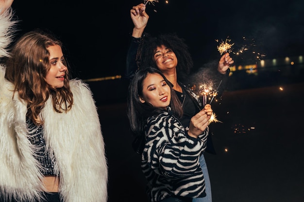 smiling young women holding sparkler enjoying in night club