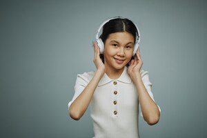 写真 お気に入りの音楽やパフォーマーを聴きながらヘッドフォンに触れる笑顔の若いアジアの女の子