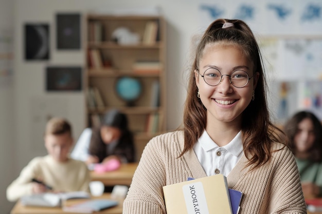 Smiling youthful schoolgirl in eyeglasses and casualawear looking at camera