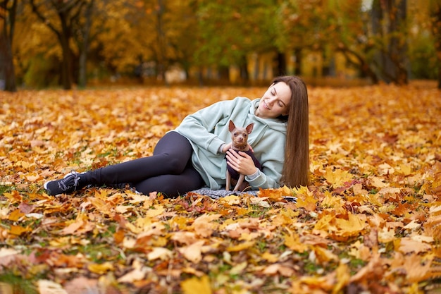 Smilling aantrekkelijke wowan liggend met hond toyterrier in het herfstpark