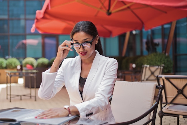 Smilling afro business woman ready for interview while sitting at table in outdoor cafe and looking at camera