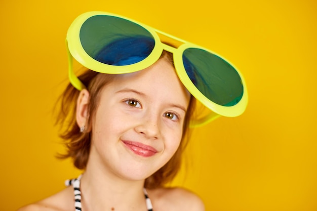 Smilling Child teenager girl in swimsuit and big sunglasses posing