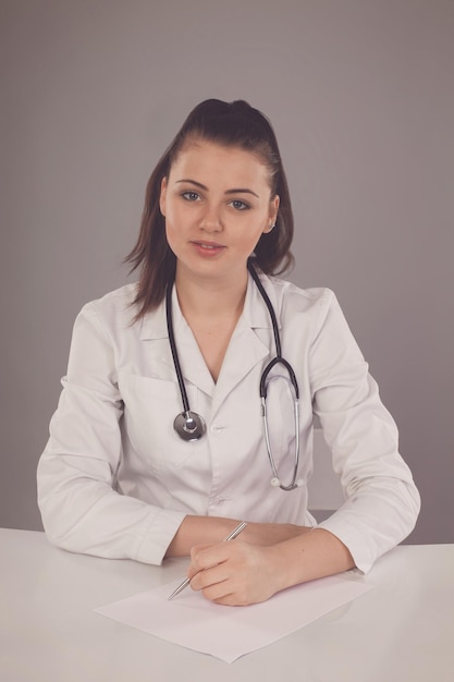 Smilling nurse is at the table with two papers