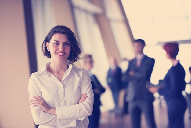 Photo smilling young business woman in front her team blured in background. group of young business people. modern bright  startup office interior.