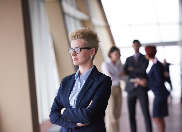 Smilling young business woman in front her team blured in background. Group of young business people. Modern bright  startup office interior.