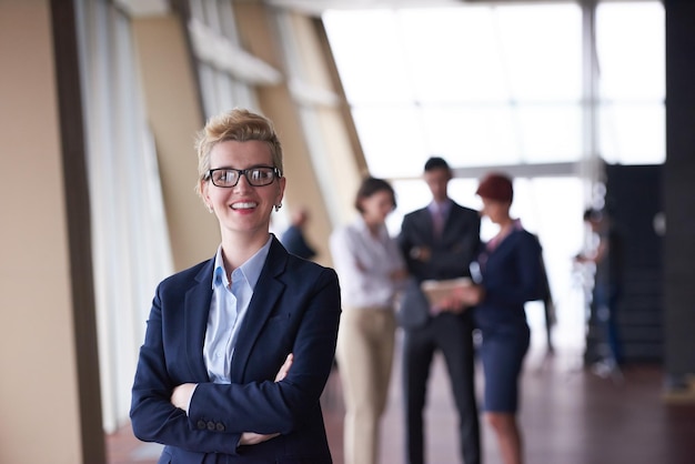 Smilling young business woman in front her team blured in background. Group of young business people. Modern bright  startup office interior.