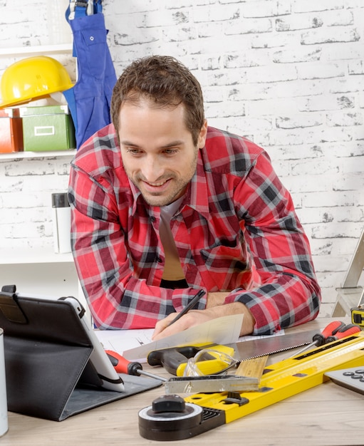 Foto smillings jonge mens die de tablet gebruiken voor diy