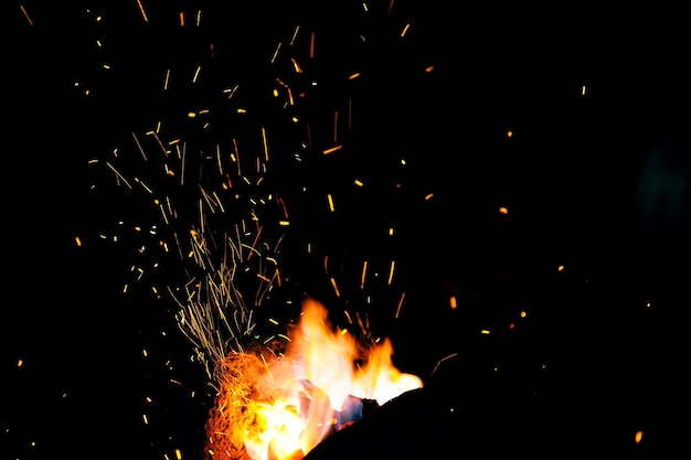 Smithy fire flame tips with sparks closeup on dark background