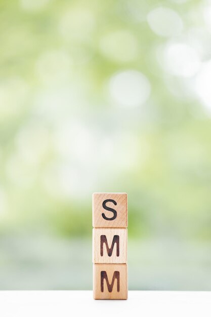 SMM-woord is geschreven op houten kubussen op een groene zomerachtergrond Close-up van houten elementen