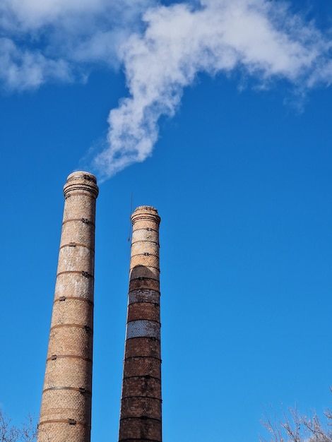 Smoke coming out of a chimney with a cloud in the sky behind it.