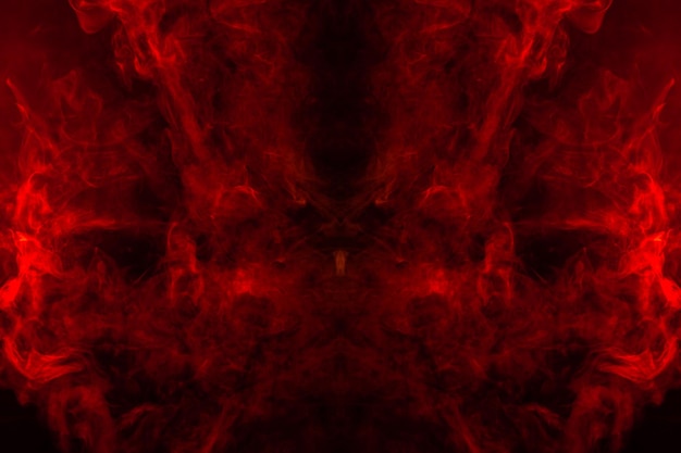 Smoke of different orange and red colors in the form of horror in the shape of the head face and eye with wings on a black isolated background soul and ghost in mystical symbol