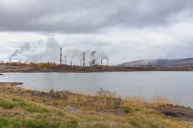 Smoke and ecology. pipes of thermal power plants against a blue sky. A stream of black smoke comes out of the right pipe