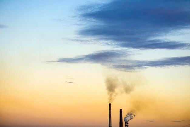 Smoke emitting from chimney against sky at sunset