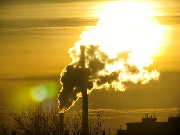 Photo smoke emitting from chimney against sky at sunset