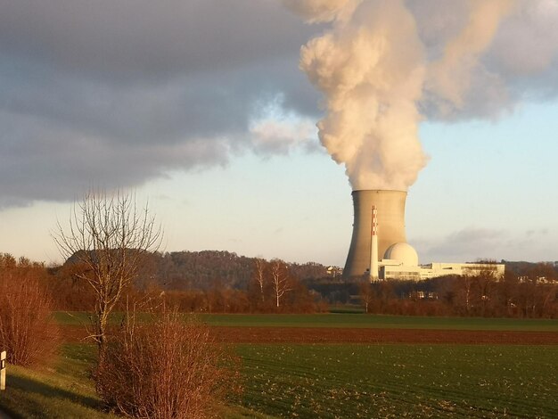 Smoke emitting from chimney on field against sky