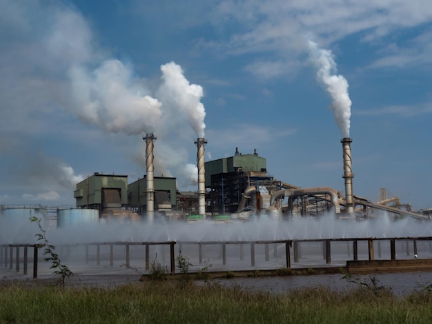 Smoke emitting from factory against cloudy sky