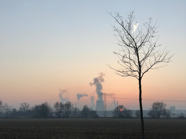 Photo smoke emitting from factory against sky at sunset