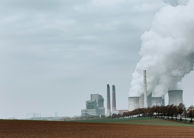 Smoke emitting from factory against sky