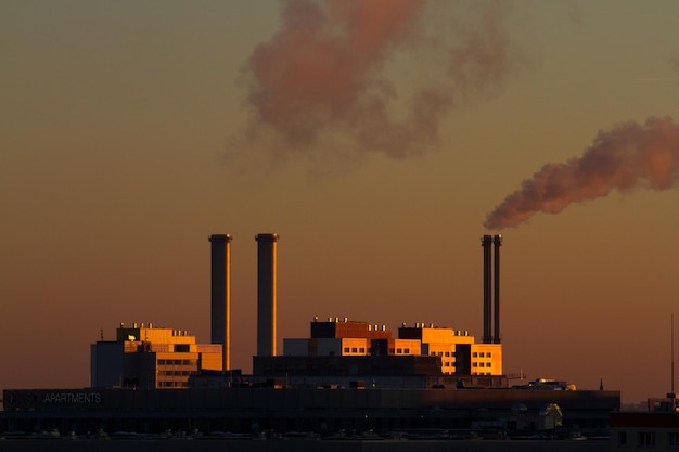 smoke emitting from industry against sky during sunset