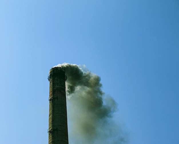 Fumo dal camino di un impianto chimico contro il cielo blu concetto ecologico