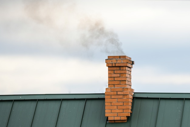 Photo smoke from the chimney, heating. smoke billowing. coming out of a house chimney against a blue sky background