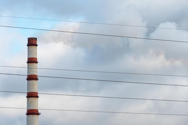 The smoke from the power plant chimney environmental pollution\
nonrenewable energy sources large chimney and electrical wires\
against a background of grey clouds environmental disaster