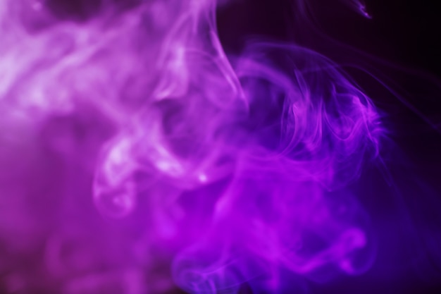 Дым на темном фоне в ярком модном фиолетовом неоновом свете.