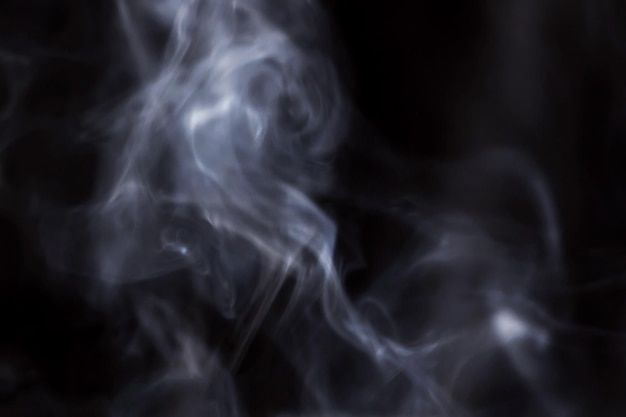 Smoke rises in the air on a black background