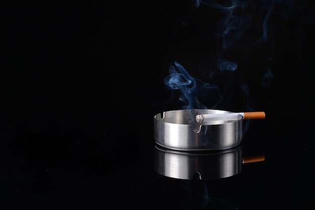 Photo smoke rising from a cigarette in an ashtray