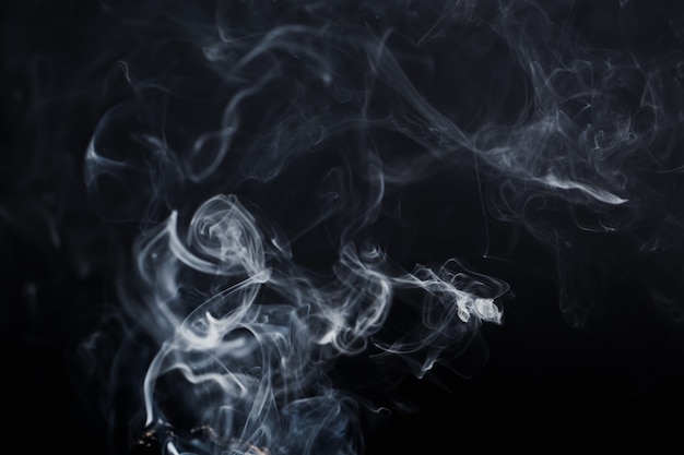 Smoke spreads in the air on dark background.