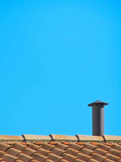 写真 澄んだ青い空を背景に屋根の上に煙が積もっている