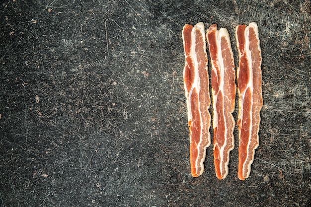 Photo smoked bacon strips on old kitchen table top view