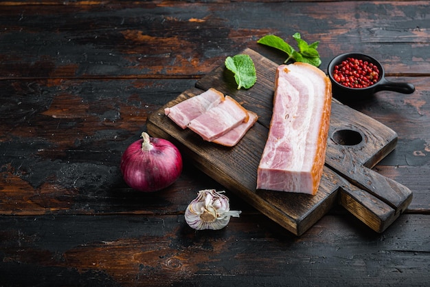 Smoked bacon, whole slab  with herbs on wooden surface with space for text.