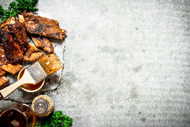 Smoked barbecue ribs with beer and herbs on a stone background