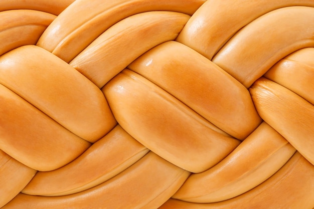 Smoked braided cheese pigtail intertwined closeup background