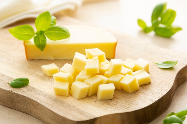 Smoked cheese on cutting board with basil, sliced cheese, dairy product