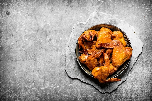 Smoked chicken wings. On a stone background.