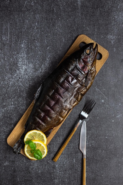 Smoked delicious whole trout on parchment Hot smoking Snack on a dark background