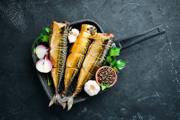 Smoked Fish Mackerel. On a black stone background. Top view. Free copy space.