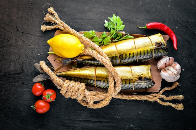 Smoked fish on Wooden board with fresh vegetables On a black wooden background Top view