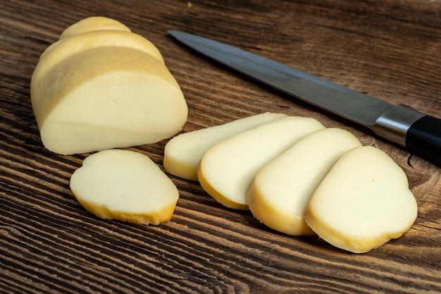 Smoked hard cheese on a wooden board with a knife