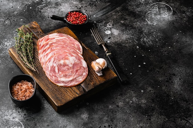 Smoked Italian sausage set, on black dark stone table background, with copy space for text
