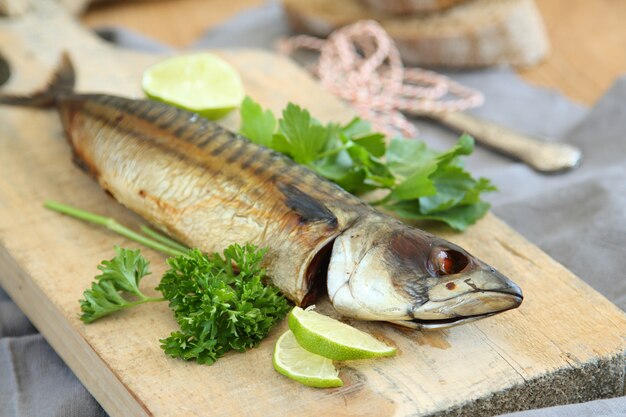 Photo smoked mackerel with lime and parsley on wooden board